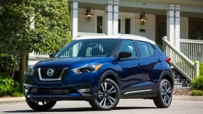 A blue 2020 Nissan Kicks parked in front of a nice home.