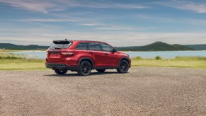 Red Toyota Highlander in the sand by the shore