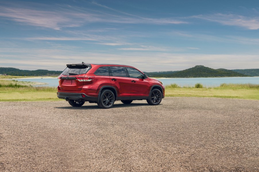 Red Toyota Highlander in the sand by the shore