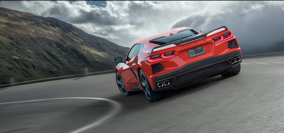 A red Corvette rounds a turn on a mountain pass.