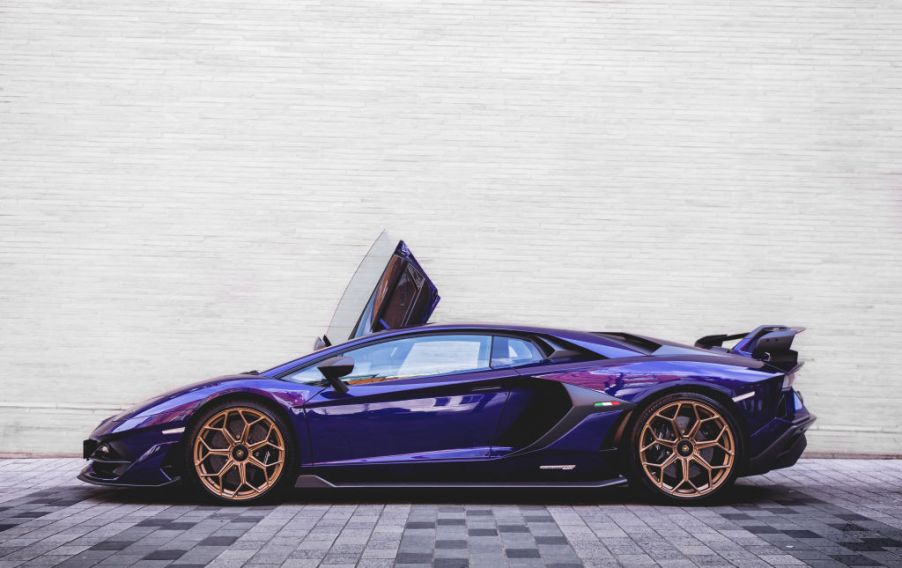 A purple 2019 Lamborghini Aventador SVJ parked in an alley.