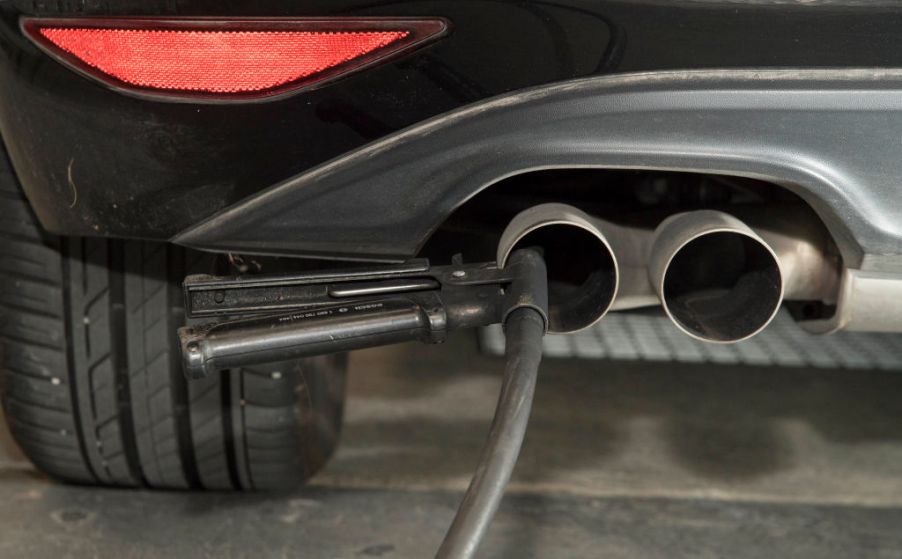 A hose for an emissions test is placed in the exhaust pipe of a vehicle