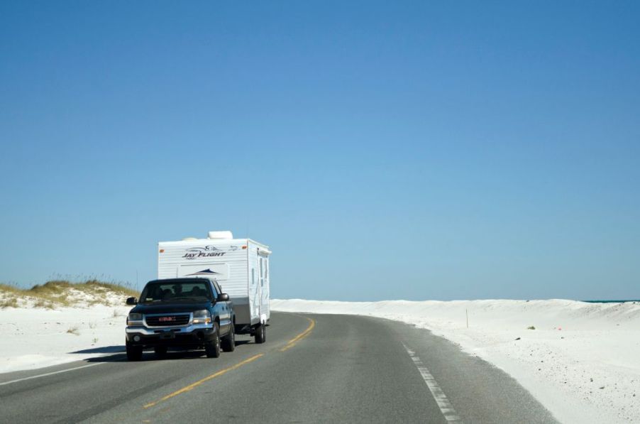 GMC pick-up truck towing a camper trailer down a Pensacola highway