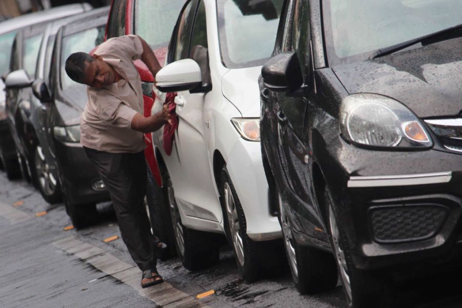 A man detailing his car. Wiping it down with a towel.