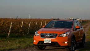 Orange Subaru Crosstrek CUV driving down a road