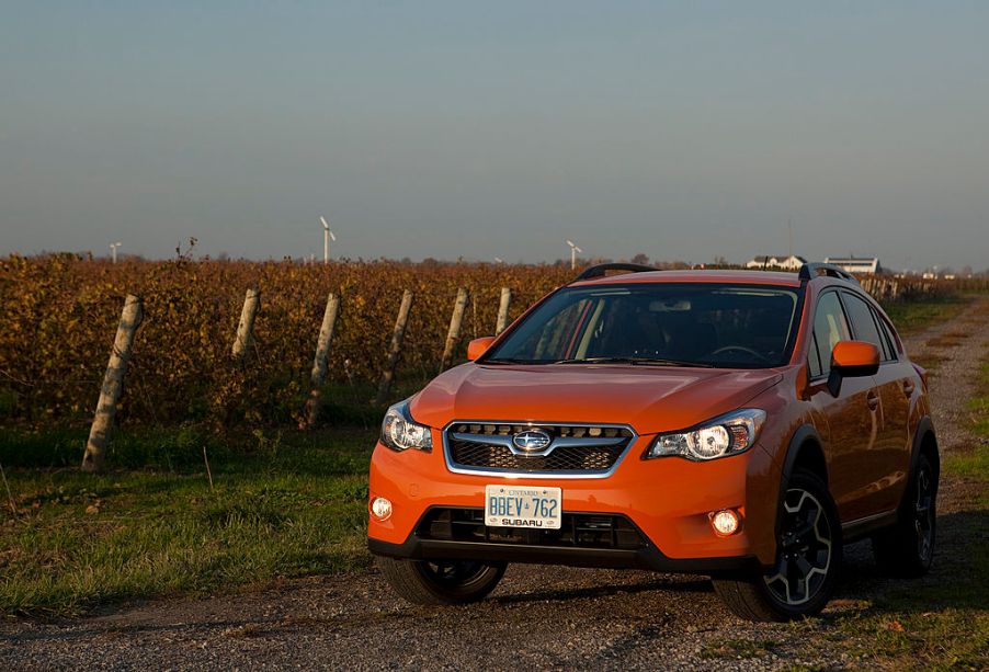 Orange Subaru Crosstrek CUV driving down a road