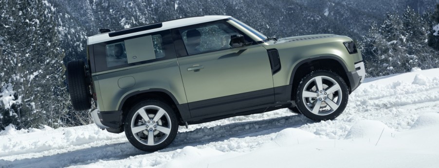 A 2020 Land Rover Defender, two-door model, ascends a hill in the snow.