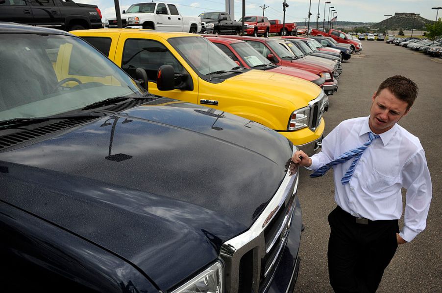 Car salesman leans against a 2005 Ford Supercab F-350 diesel truck