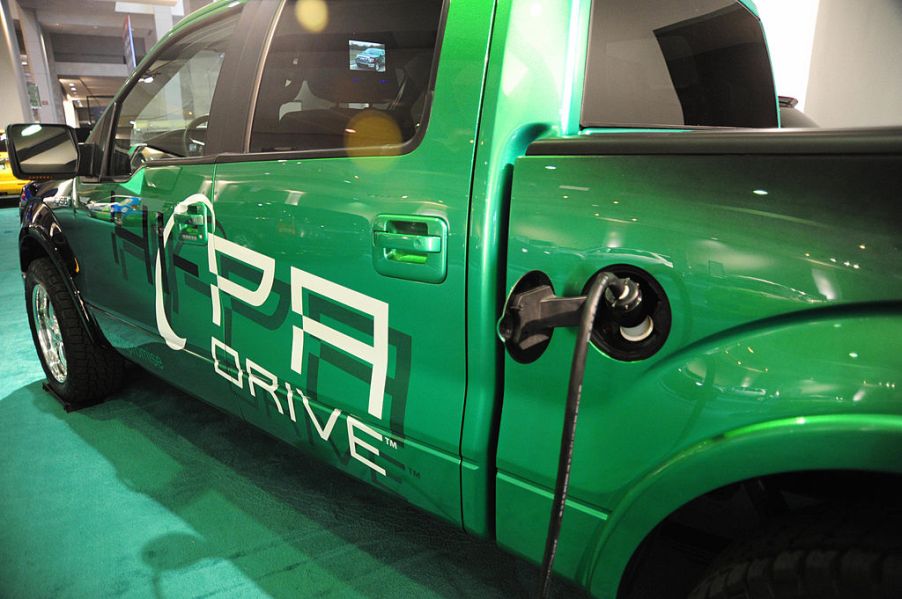 An electric Ford F-150 on display plugged into a charger.