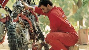 Man inspects his motorcycle for repairs