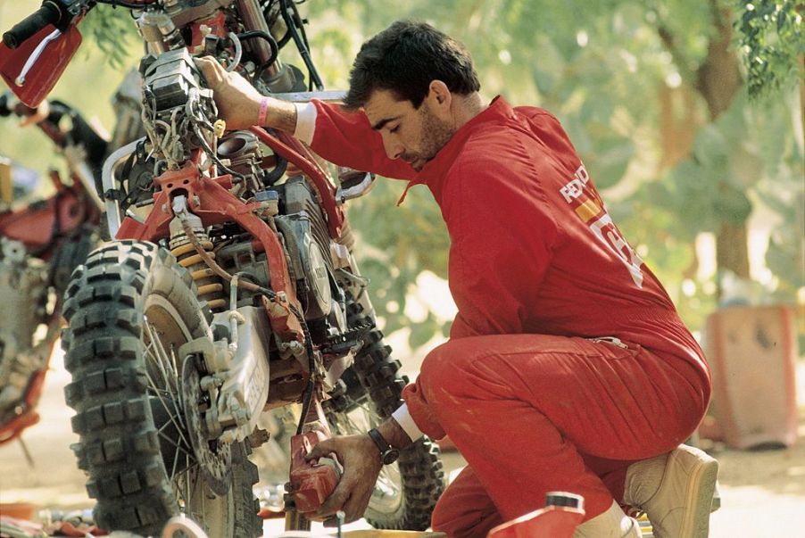 Man inspects his motorcycle for repairs