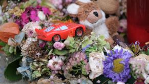 A toy car lies among flowers and candles left by mourners at the site of a pedestrian accident