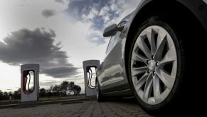 A Tesla car sits parked at a supercharger