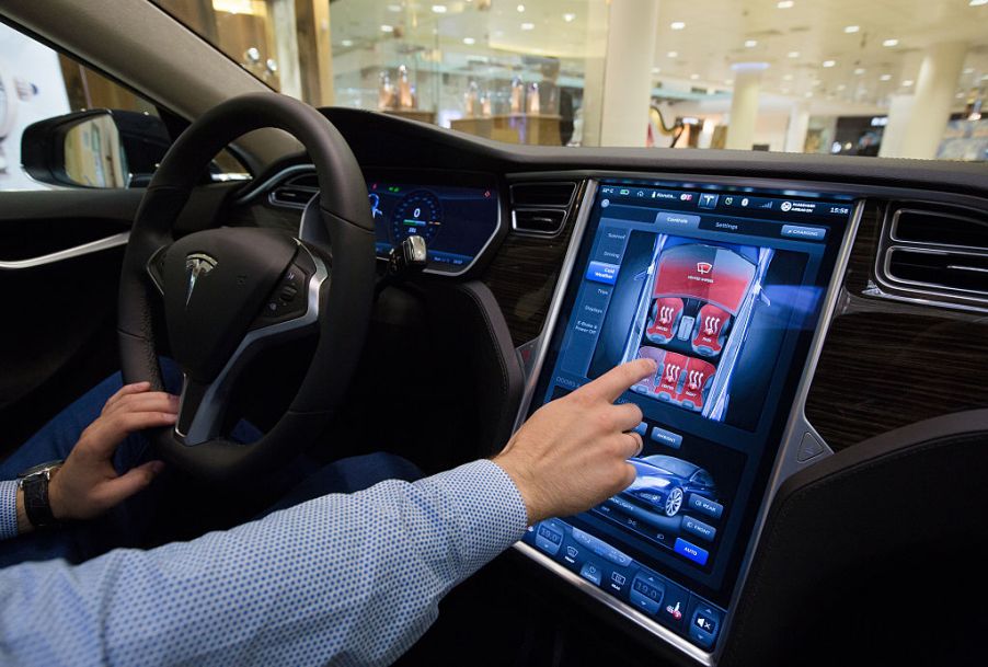 Man sitting in a Tesla using the infotainment screen.