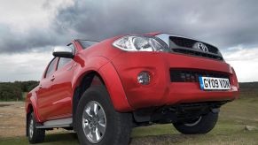 A red Toyota Hilux driving up a hill.