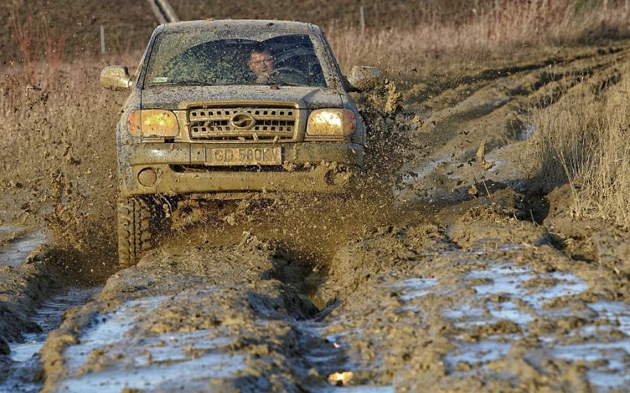 A truck off-roading through a big puddle of mud.