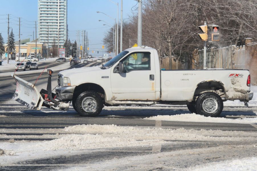 A white pickup truck with a snowplow attached.