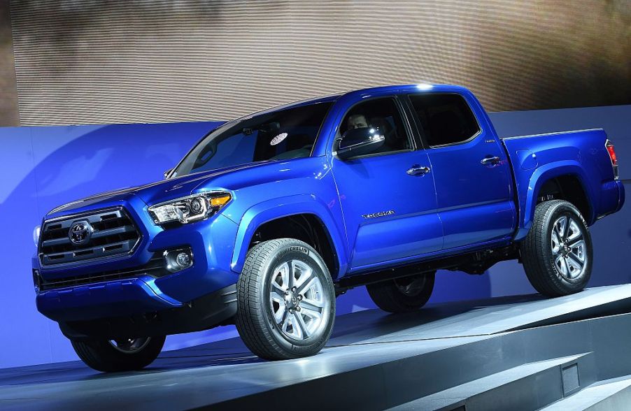 A blue Toyota Tacoma being unveiled at an auto show.