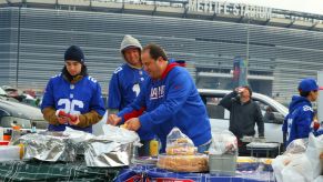 Giants fans tailgating before a game with a truck in the background.