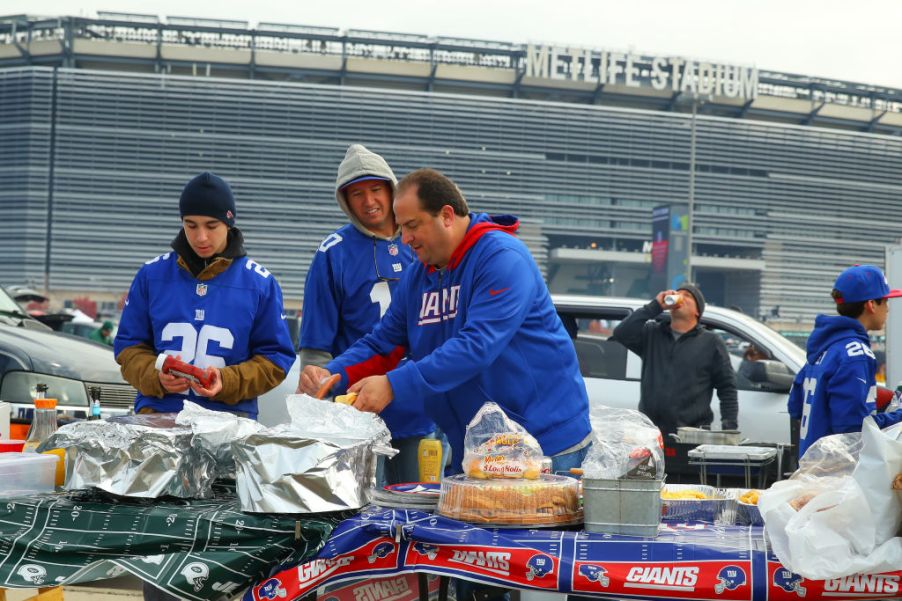 Giants fans tailgating before a game with a truck in the background.