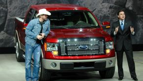 Two people showing off a Ford F-150 at an auto show.