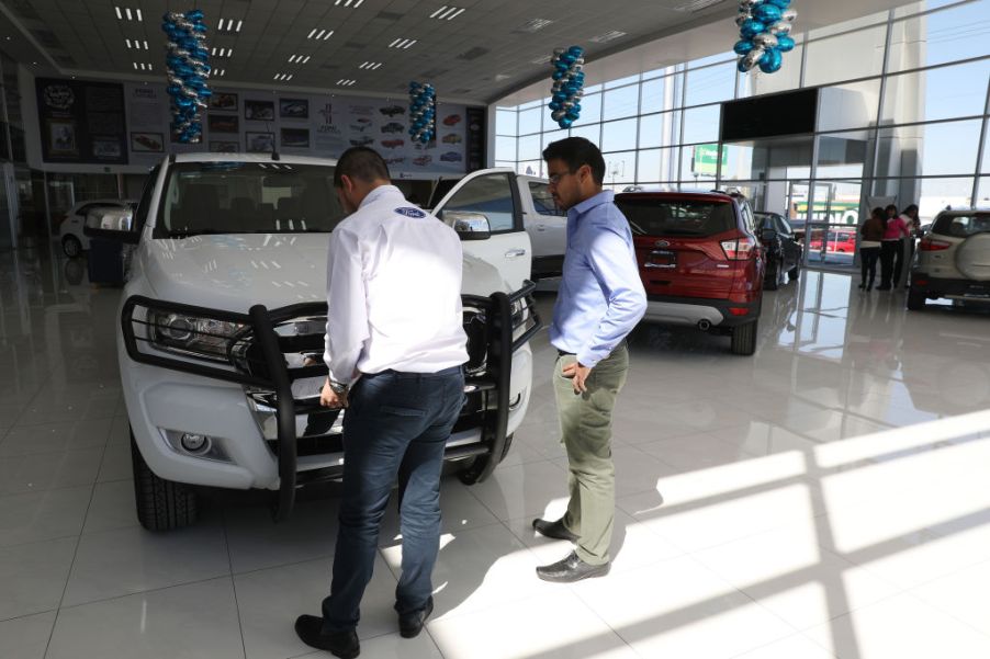 An employee shows a customer a Ford Ranger truck at a dealership