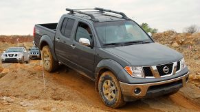 A Nissan Frontier climbing over a dirt hill.