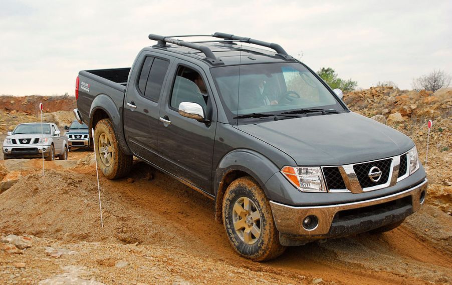 A Nissan Frontier climbing over a dirt hill.