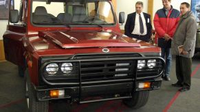 Three men looking at a truck with a grille guard