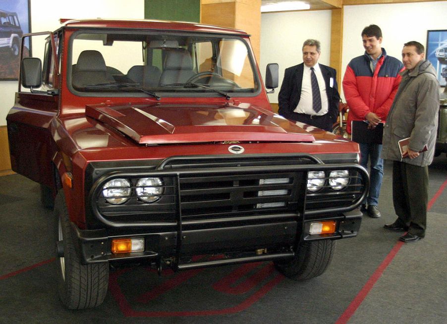 Three men looking at a truck with a grille guard