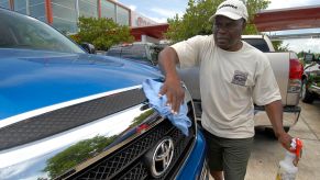 A person wiping the grille of a truck clean.