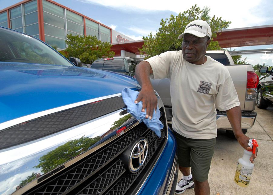 A person wiping the grille of a truck clean.