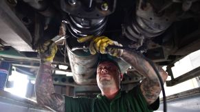 A truck mechanic works on the underside of a diesel truck