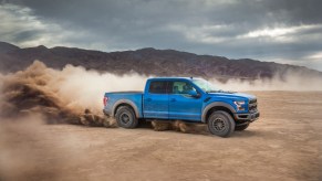 A bright blue 2020 Ford F-150 driving through the sand.