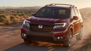 A red Honda Passport runs through a dirt road.