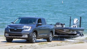 A gray 2020 Honda Ridgeline towing a boat through sand.