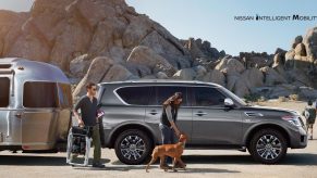 A gray 2020 Nissan Armada parked near the desert with a family and dog.