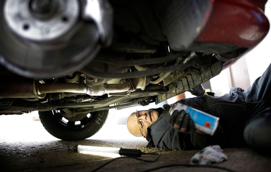 A man works on the under side of a car.