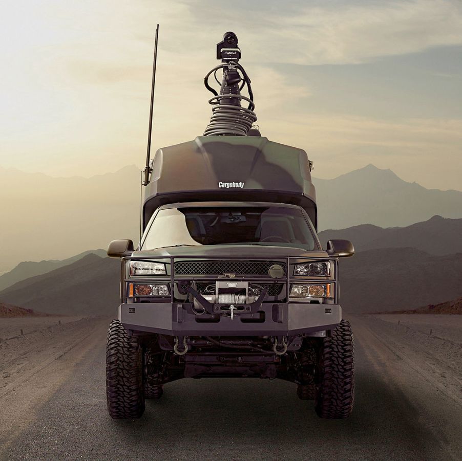 A Chevy military truck driving down a dirt road