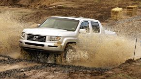 An older Honda Ridgeline driving through a puddle