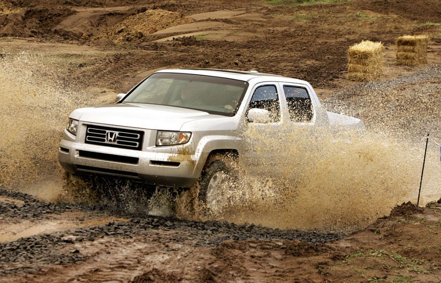 An older Honda Ridgeline driving through a puddle