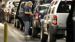 A man helping to assemble a Jeep Liberty in a factory