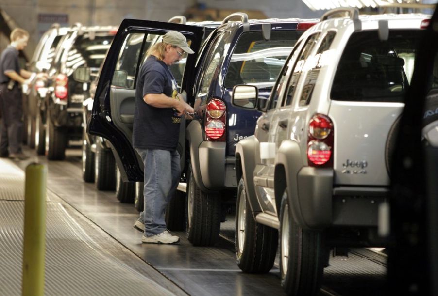 A man helping to assemble a Jeep Liberty in a factory