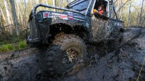 An off-roading truck drives through a big puddle of mud.