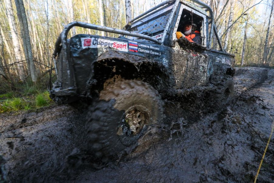 An off-roading truck drives through a big puddle of mud.