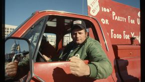 A farmer hanging out the window of his pickup truck