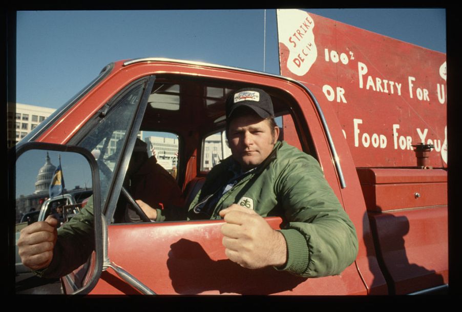 A farmer hanging out the window of his pickup truck