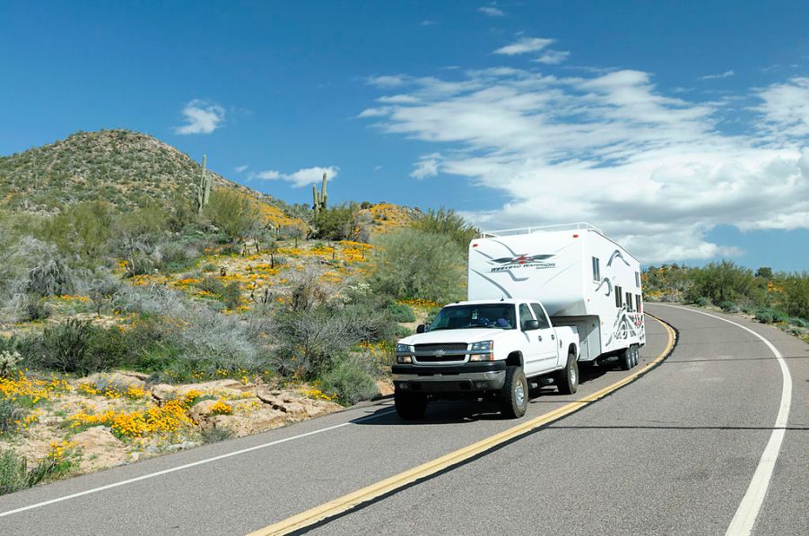 A truck towing a large RV down the road