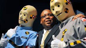 An NHTSA employee poses with crash test dummies