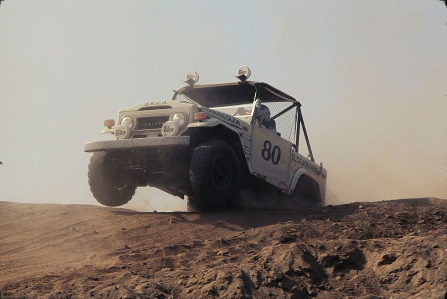 A Toyota FJ series truck jumps over a sand dune